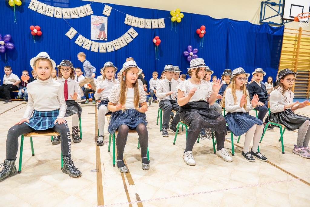 Na zdjęciu grupa uczniów klasy klas 1. 2 i 3 tańcząca z kapeluszami dla dziadków